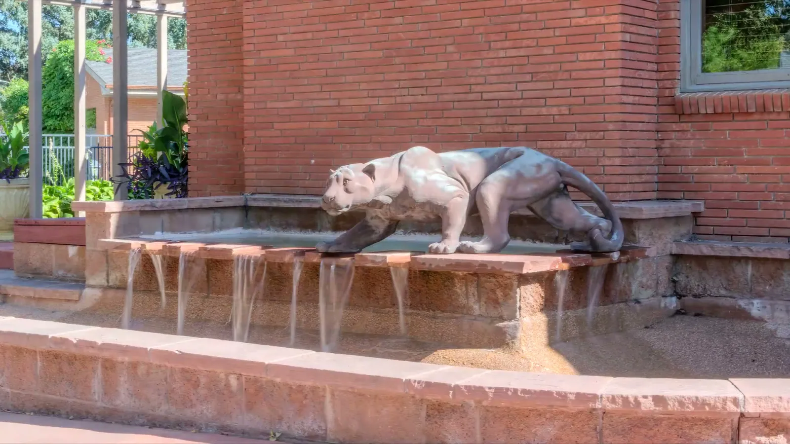 The lion fountain against the brick main-house wall.